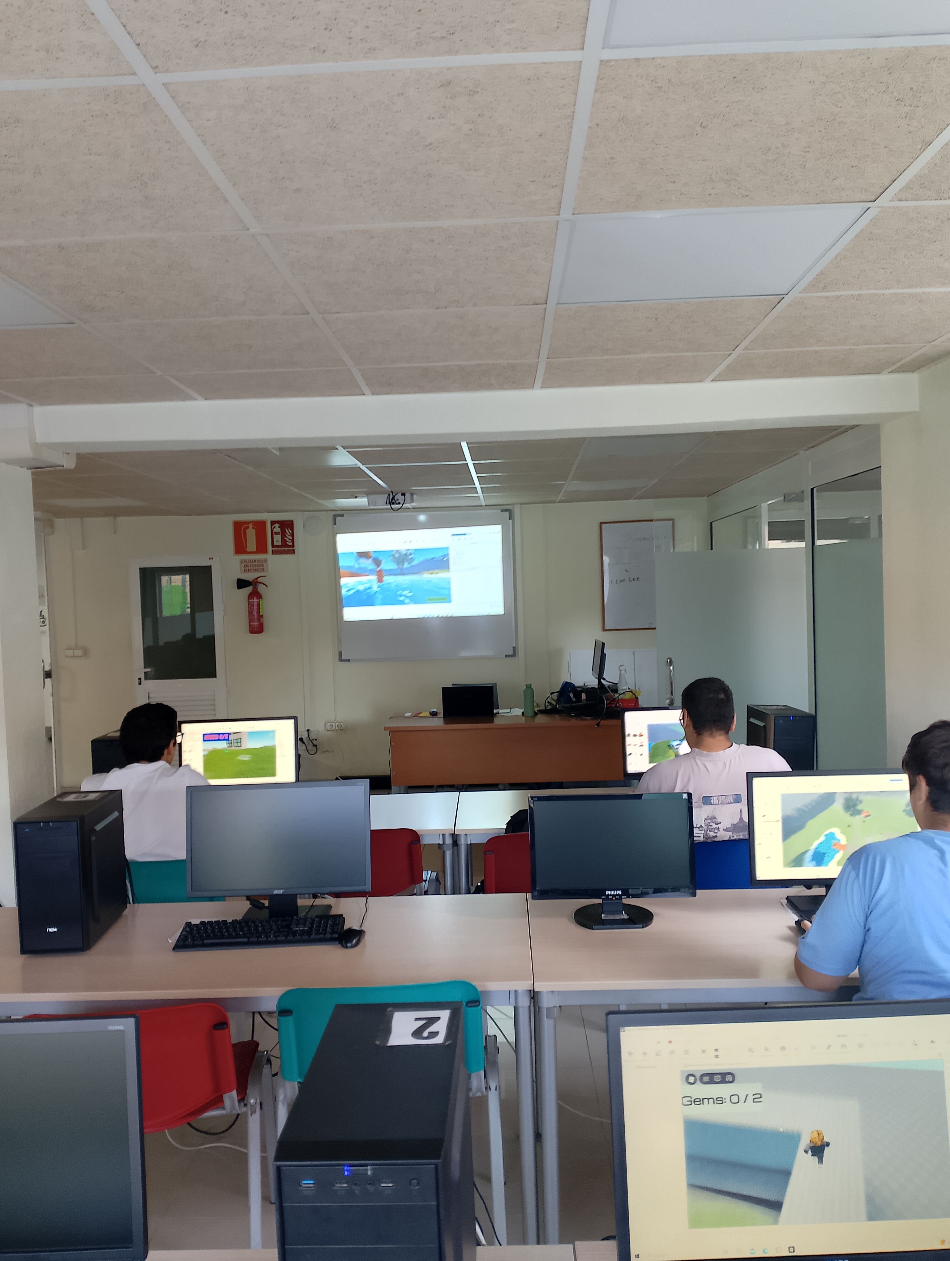 Alumnado de espaldas trabajando con Roblox Studio en un aula de ordenadores